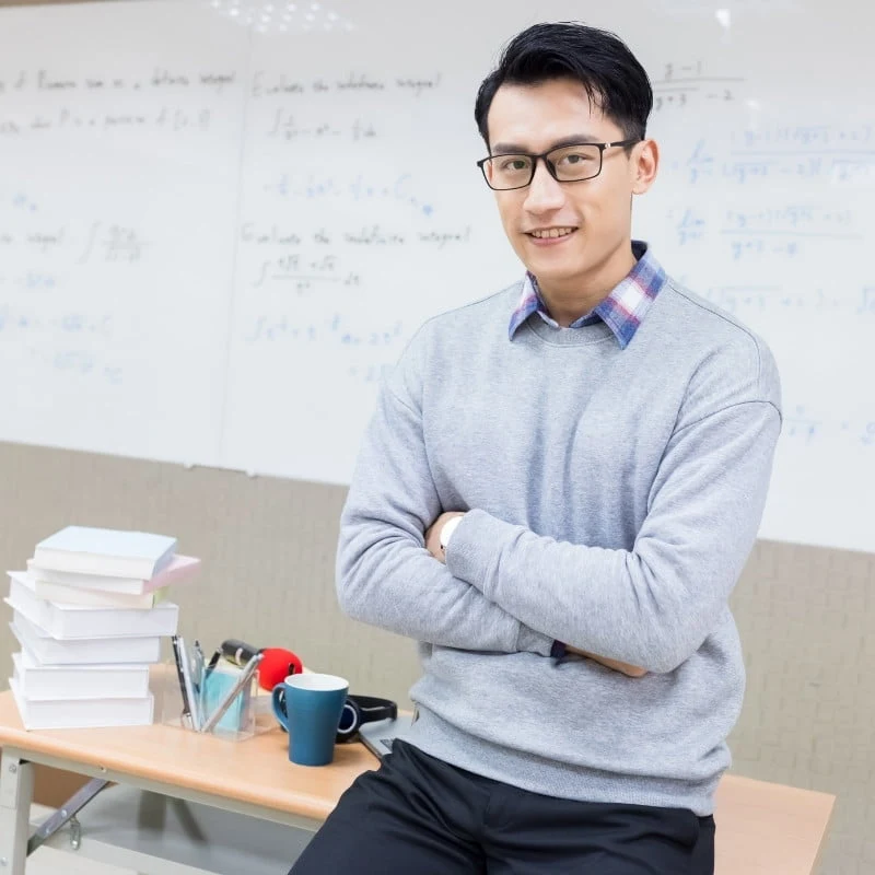 Erudite Tuition teacher standing beside a study table.